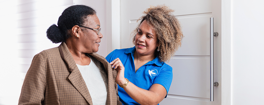 A Visiting Angels caregiver gently supporting an elderly woman with dementia, highlighting compassion and understanding in dementia care.