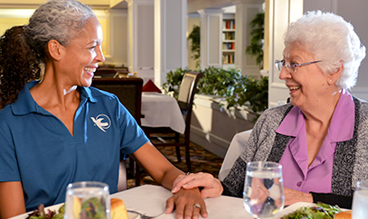 A Visiting Angels caregivier sitting with an elderly woman, engaging in conversation over tea, symbolizing companionship in home care services.